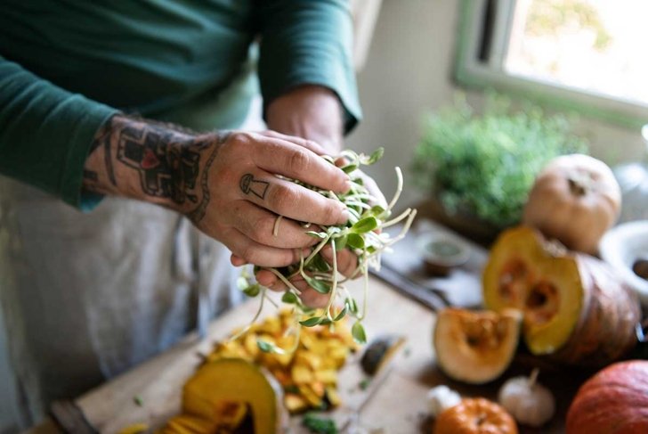 Tattooed hands holding vegetables cooking in the kitchen
