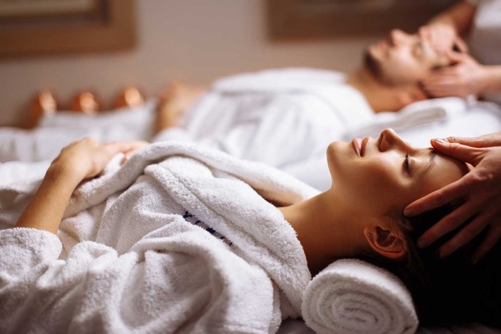 Young couple receiving head massage at beauty spa