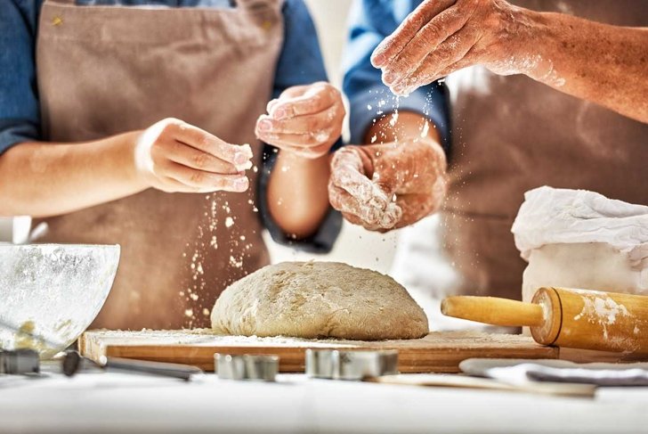 Close up view of bakers are working. Homemade bread. Hands preparing dough on wooden table.