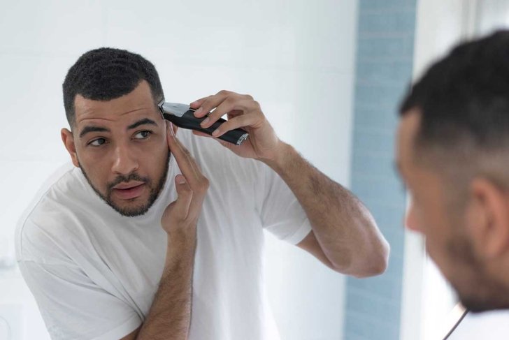 Mixed race male trimming and grooming in his bathroom