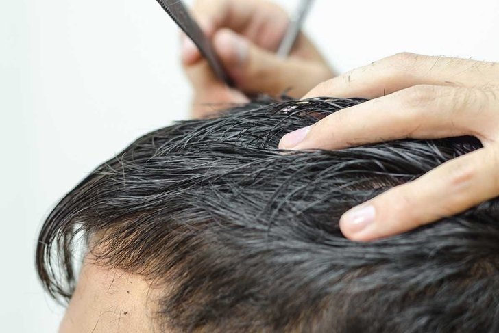 hairdresser cuts a customer piece of hair